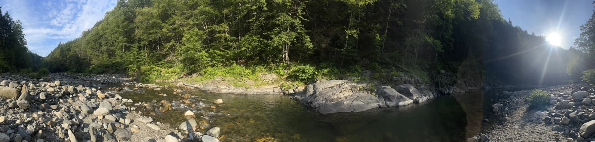 Wide scenic view of Rock River Vermont swimming holes in Newfane with clear water, forest, and river stones