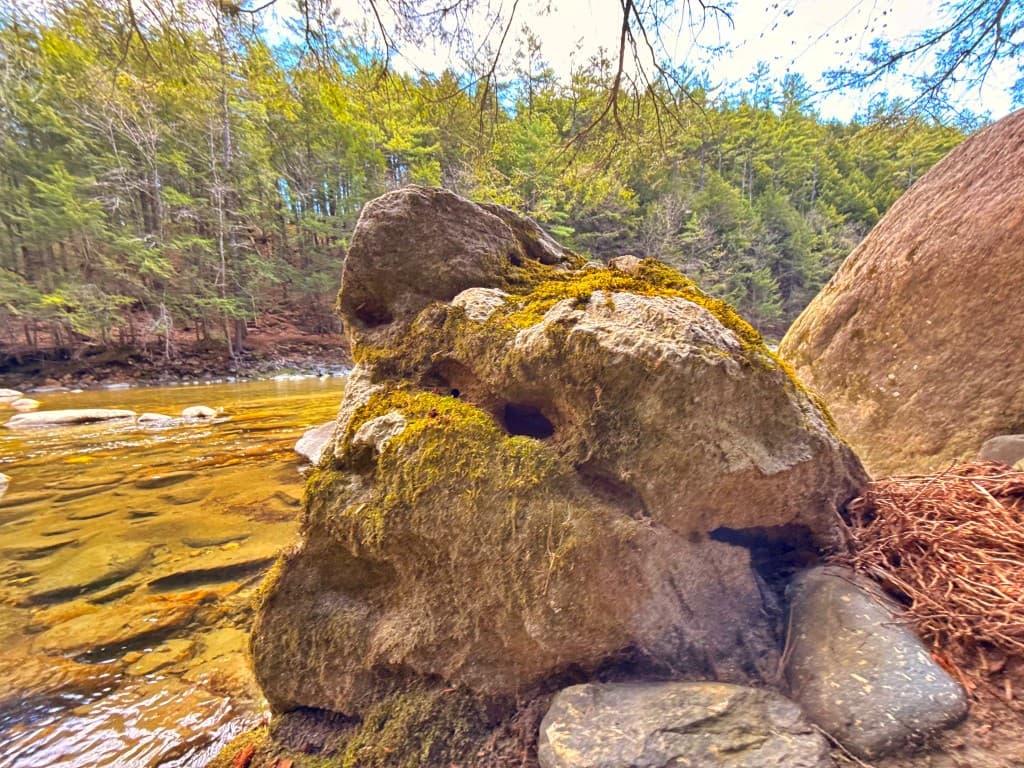 A large moss-covered boulder beside the clear water of Rock River along the Dummerston and Newfane corridor