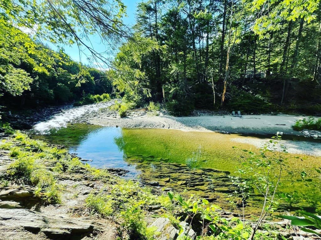 Calm river bend with sandy shore and summer chairs — southern Vermont
